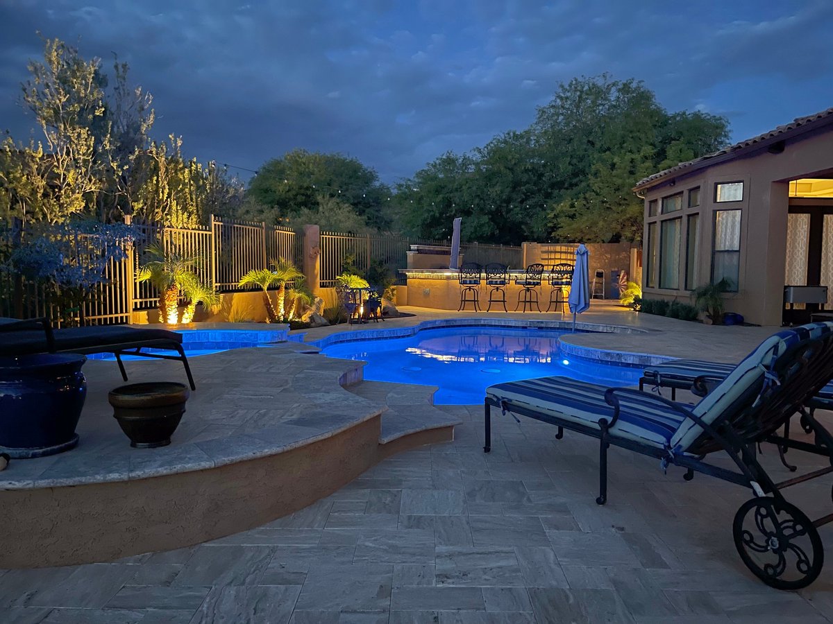 A desert landscaped yard in Arizona featuring a travertine pool deck