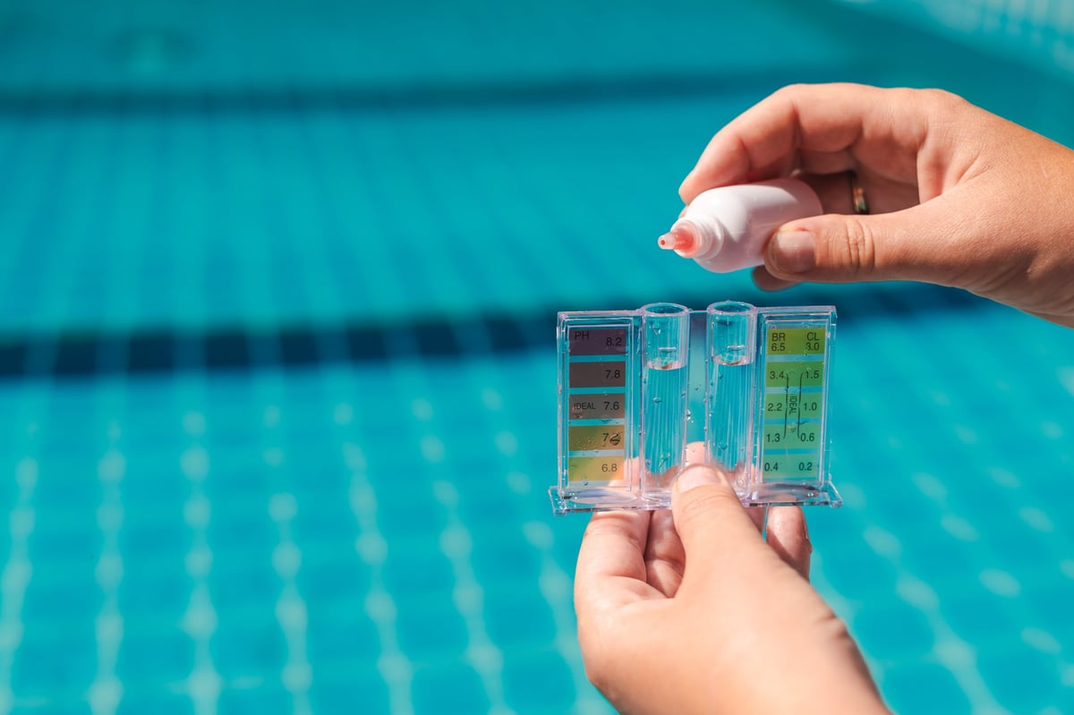 Hand holding a pool water test kit to measure pH and chlorine levels at an Arizona residential pool