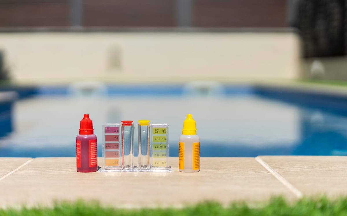 Close-up of a pool water testing kit with reagent bottles used to measure pH and chlorine in a backyard pool
