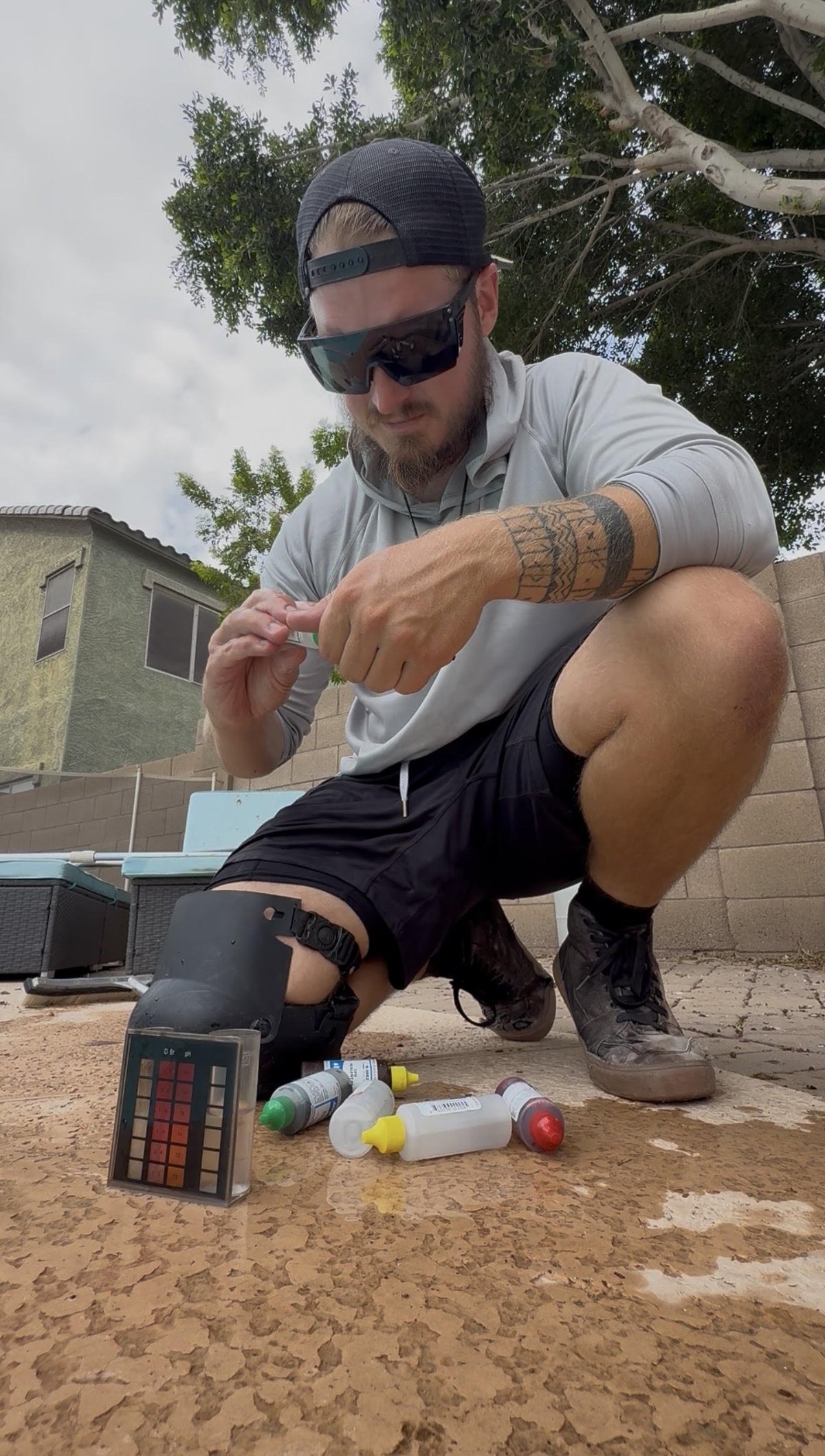 Dan, owner and technician at Runestone Pool Care, crouching outdoors with photography color chart and lighting equipment